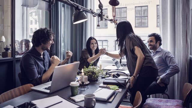 Happy business women holding hands in meeting at creative office SMALL